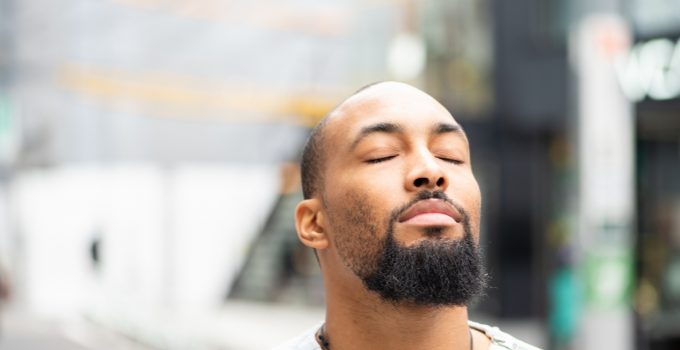 Man standing outside with his eyes closed, enjoying a moment of peace