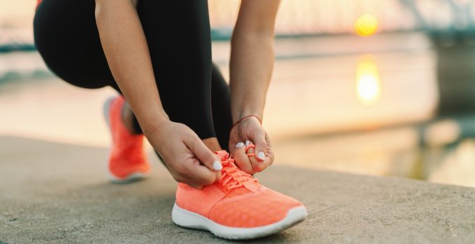 A woman stops to tie the laces on her trainers whilst out for a run